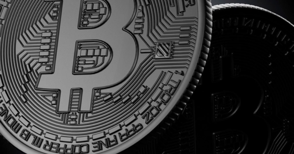 A metal bitcoin token lit from the left with a second coin in shadow behind it