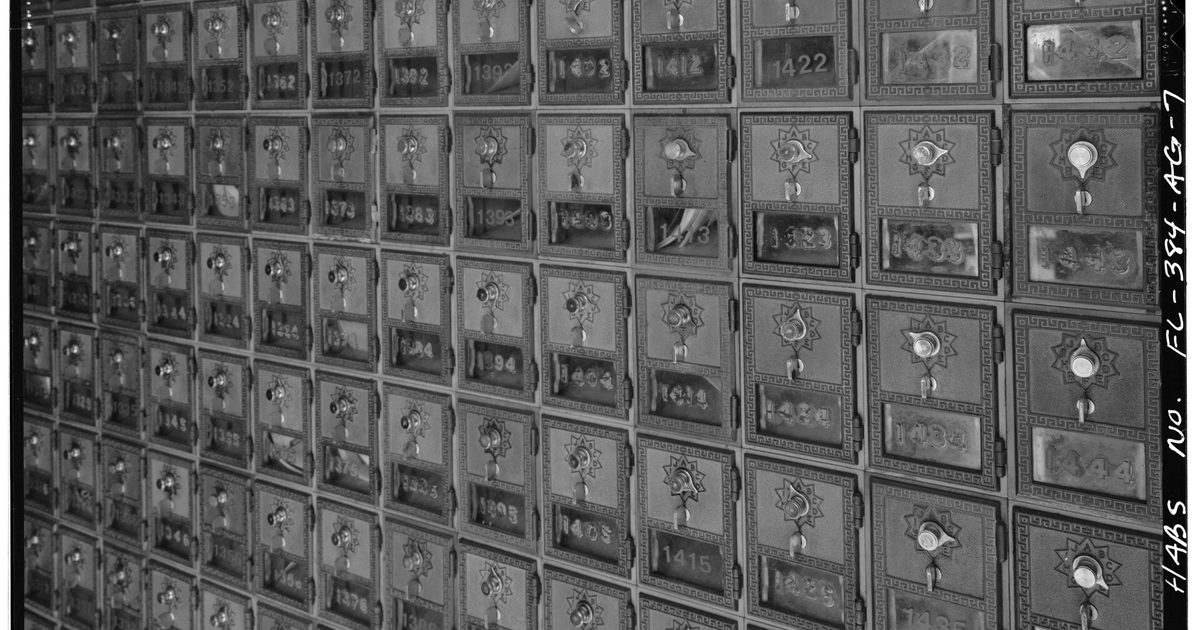 A wall of numbered post office boxes, each with a small dial lock