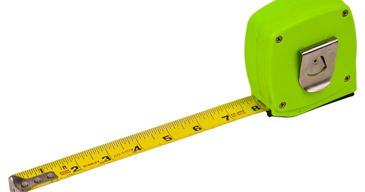 A yellow tape measure pulled out of a bright green case, on a white background