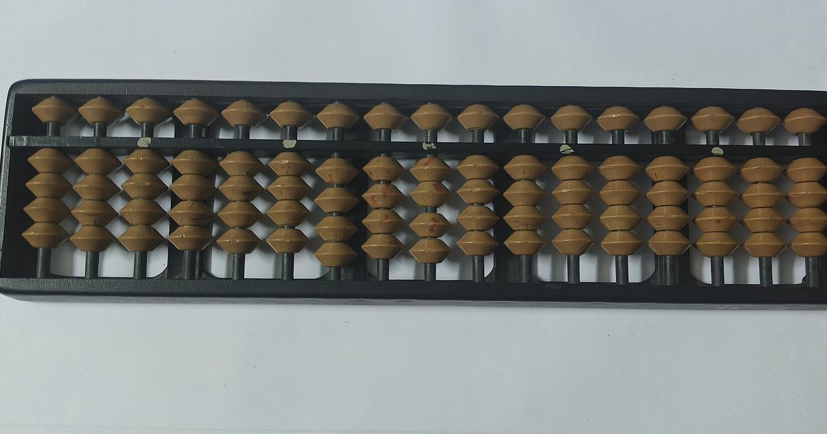 An abacus with rows of tan wooden beads on a black frame, on a white surface