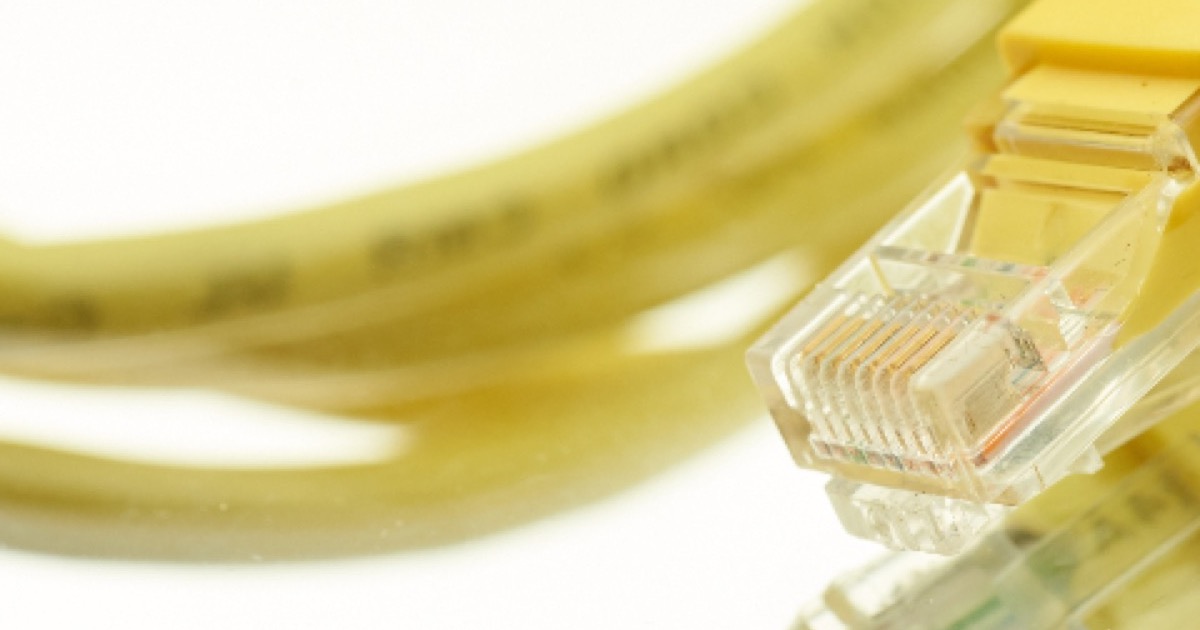 A coiled yellow ethernet cable with two RJ45 plugs, on a white background